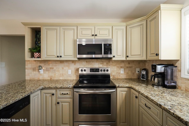 kitchen with appliances with stainless steel finishes, cream cabinetry, backsplash, and light stone counters