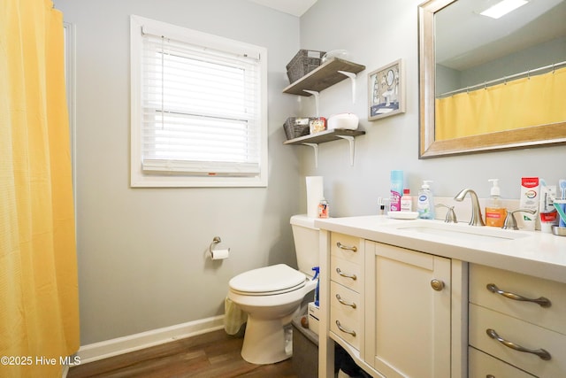 bathroom with toilet, baseboards, wood finished floors, and vanity