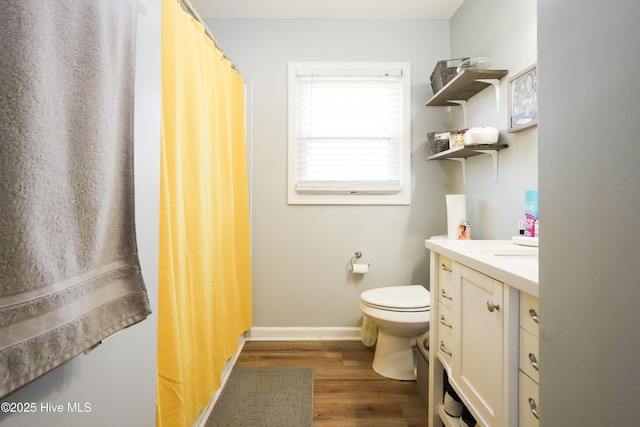 full bath with toilet, baseboards, wood finished floors, and vanity