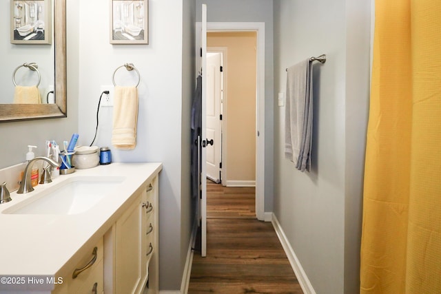 full bathroom with vanity, baseboards, and wood finished floors