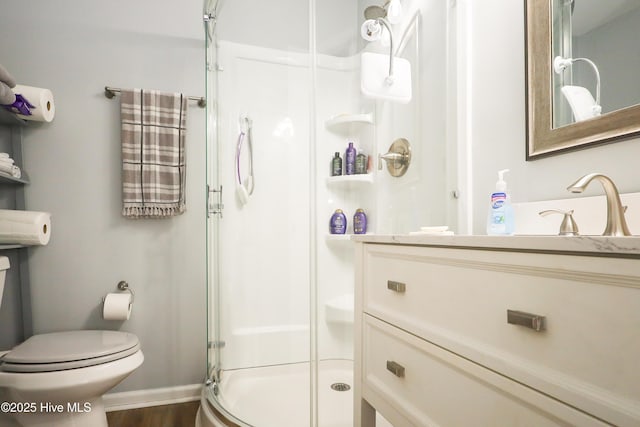 bathroom with a stall shower, baseboards, vanity, and toilet