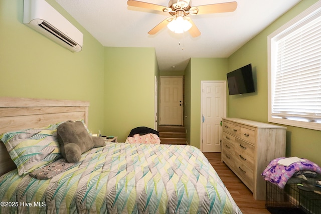 bedroom featuring light wood finished floors, a ceiling fan, and a wall mounted AC