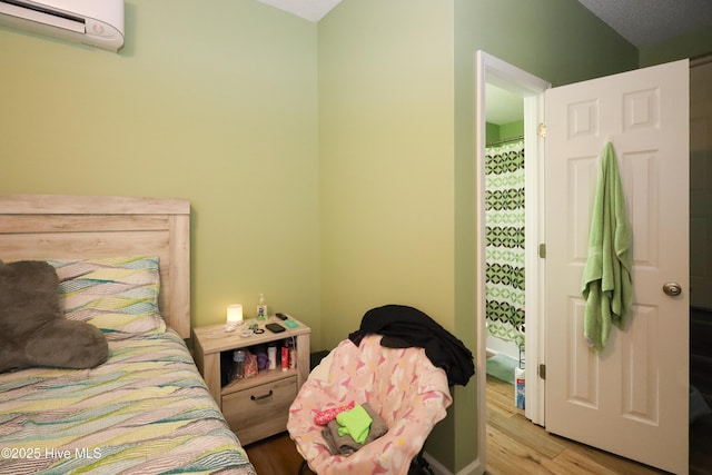 bedroom featuring a wall mounted AC and light wood-style flooring