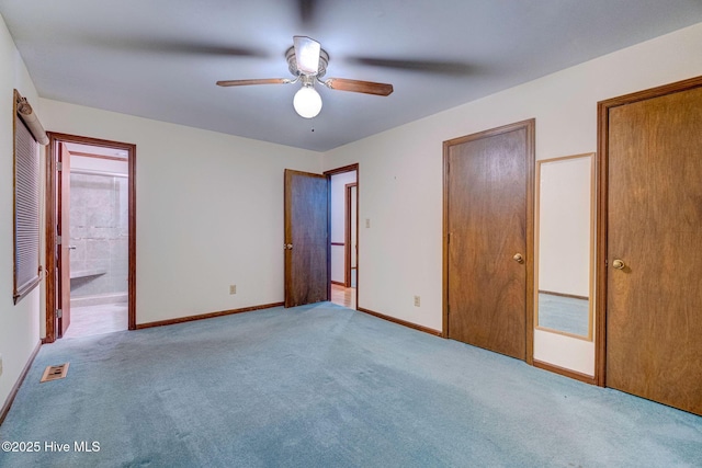 unfurnished bedroom featuring ceiling fan, light colored carpet, and ensuite bath