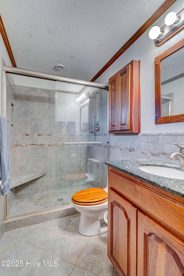 bathroom featuring an enclosed shower, vanity, toilet, and a textured ceiling