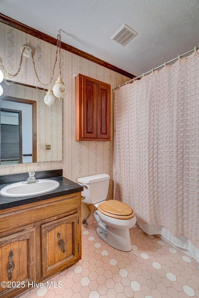 bathroom with toilet, a shower with curtain, a textured ceiling, ornamental molding, and vanity