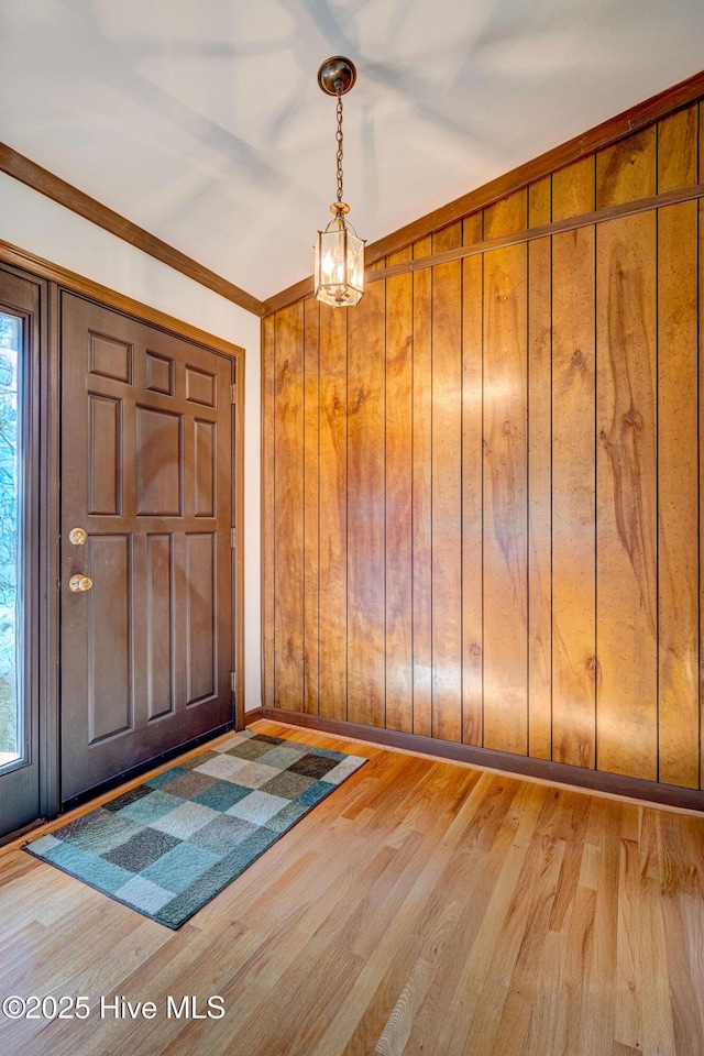 entrance foyer featuring hardwood / wood-style flooring, ornamental molding, and wooden walls