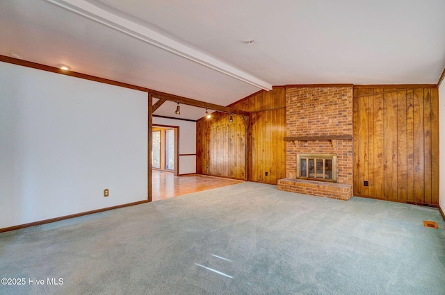 unfurnished living room with vaulted ceiling with beams, a fireplace, light colored carpet, and wood walls