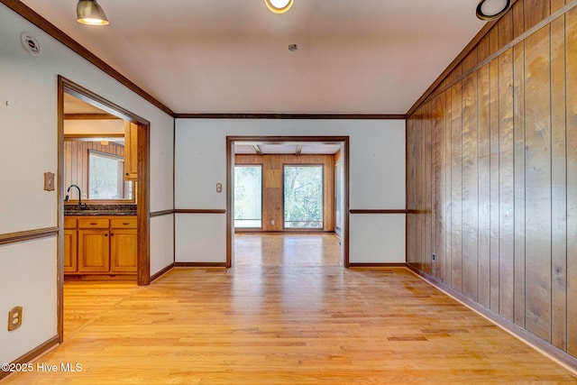 interior space featuring sink, crown molding, light hardwood / wood-style floors, and wood walls