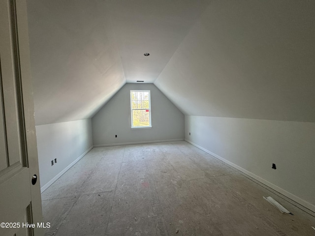 additional living space with baseboards and lofted ceiling