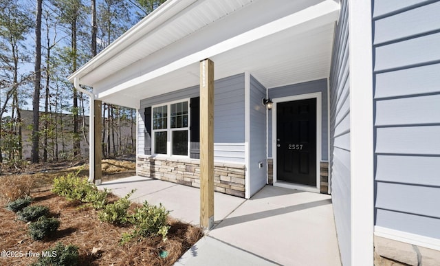 property entrance featuring covered porch and stone siding