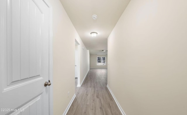 corridor featuring light wood-style flooring and baseboards