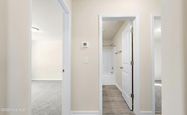hallway featuring baseboards and carpet floors