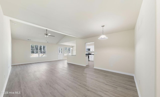 unfurnished living room featuring hardwood / wood-style flooring, ceiling fan, and vaulted ceiling