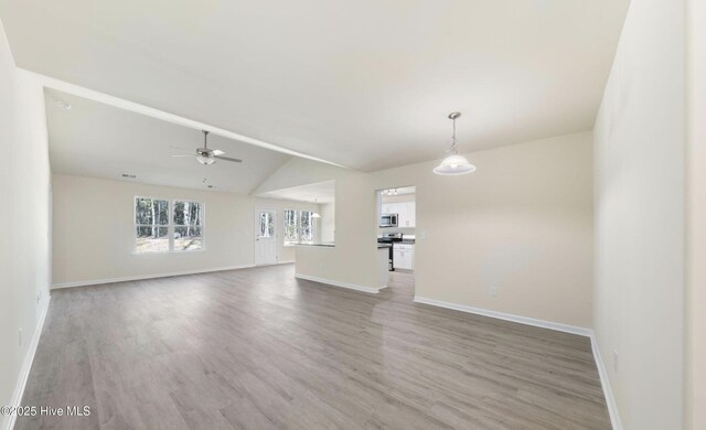 unfurnished living room with ceiling fan, light wood-type flooring, and baseboards