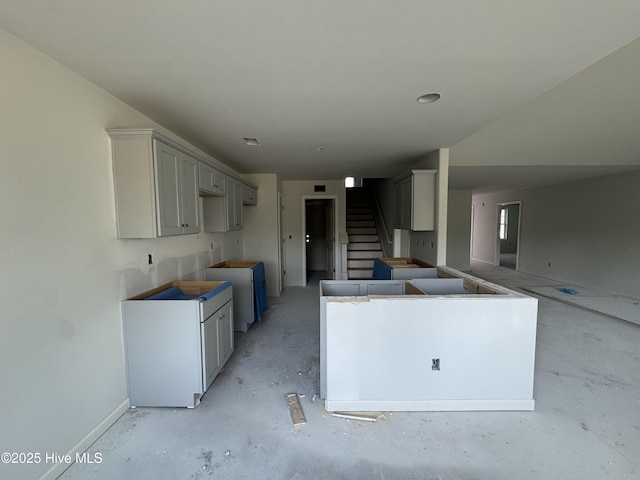 kitchen with unfinished concrete floors, gray cabinetry, and baseboards