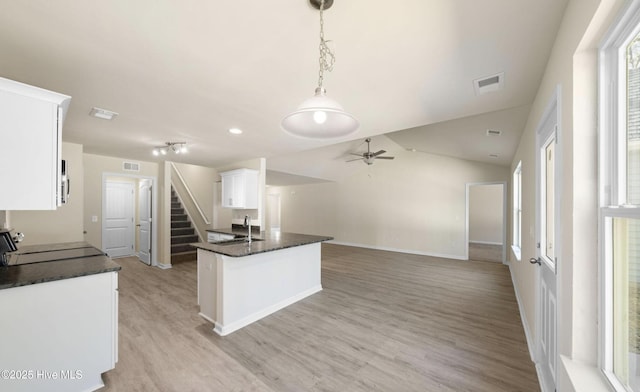 kitchen featuring light wood-style flooring, white cabinetry, a ceiling fan, stove, and a sink