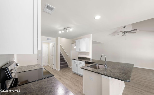 kitchen featuring stainless steel electric range, a peninsula, a ceiling fan, visible vents, and a sink