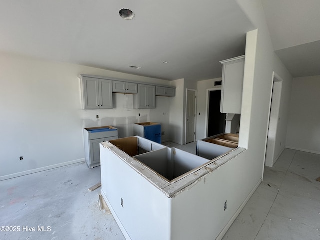 kitchen with gray cabinets, a peninsula, and baseboards
