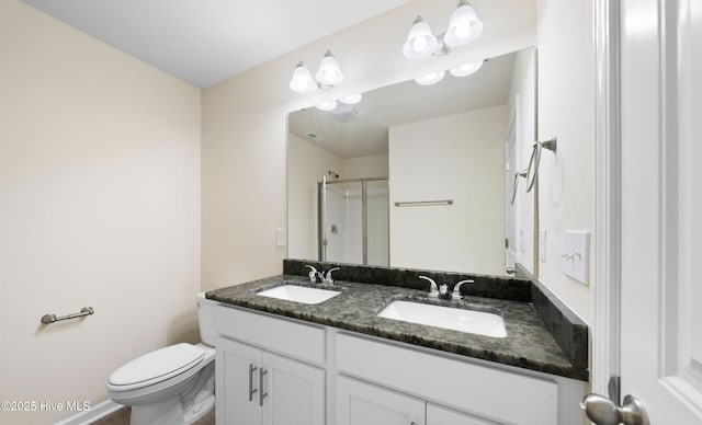 bathroom with a shower stall, double vanity, a sink, and toilet