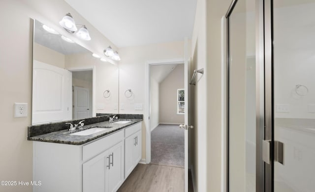 full bath featuring a sink, baseboards, double vanity, and wood finished floors
