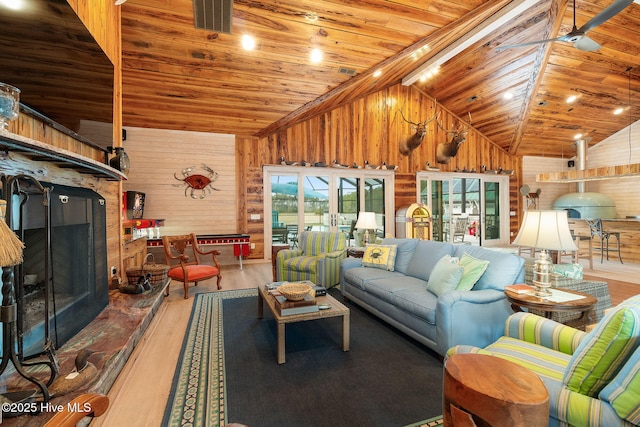 living area with wood finished floors, wooden walls, a fireplace with raised hearth, and wooden ceiling