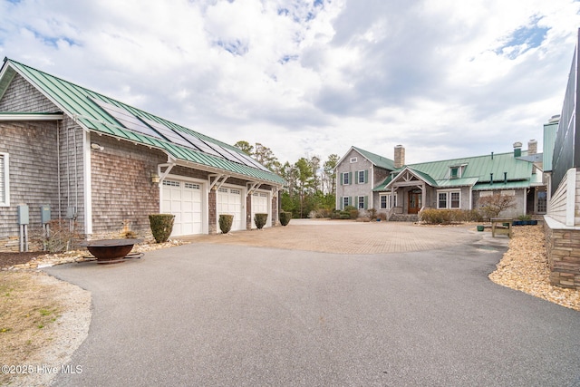 exterior space featuring community garages, metal roof, a chimney, and a standing seam roof