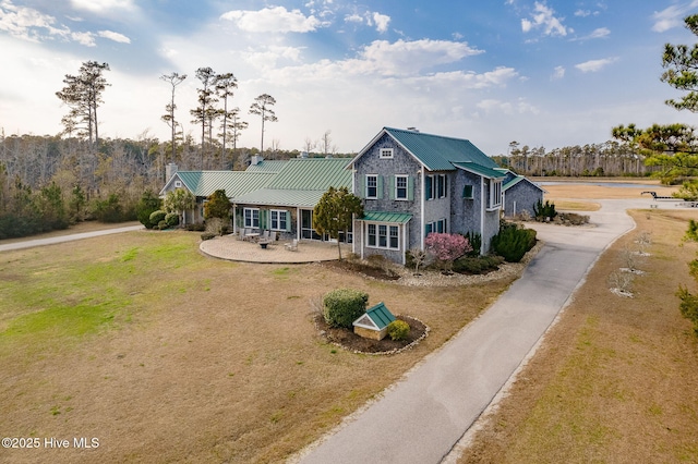 traditional-style house featuring metal roof, a patio area, a front lawn, and a standing seam roof