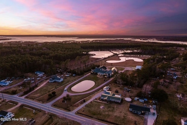 aerial view at dusk featuring a water view