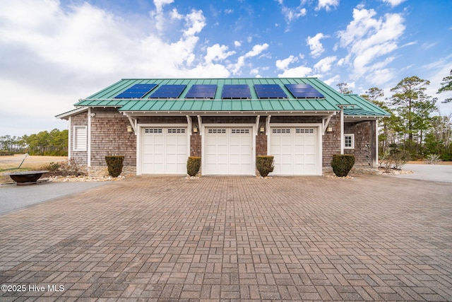 view of front facade featuring decorative driveway, solar panels, metal roof, and a standing seam roof