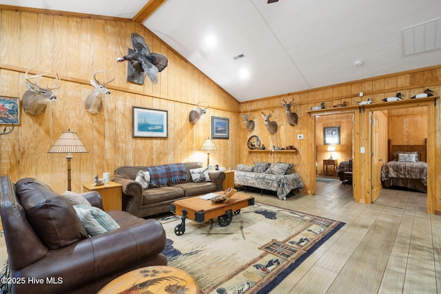 living area with visible vents, wood walls, vaulted ceiling with beams, and wood finished floors