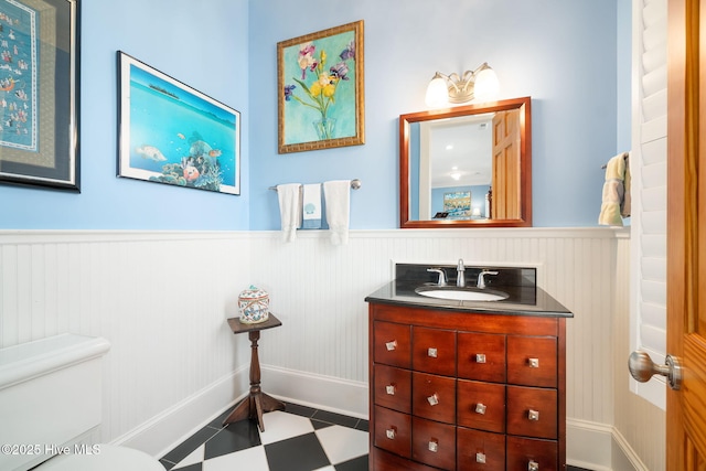 bathroom featuring tile patterned floors, a wainscoted wall, toilet, and vanity