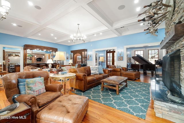 living room featuring beam ceiling, wood finished floors, coffered ceiling, and a large fireplace