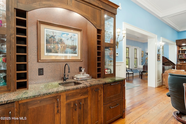 bar featuring ornamental molding, light wood-type flooring, and a sink