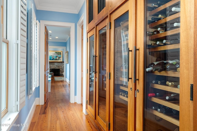 hallway with light wood-type flooring, crown molding, and baseboards