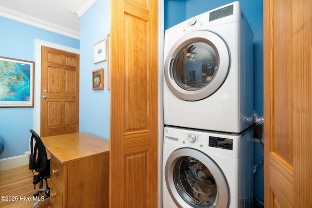 washroom with stacked washer / drying machine, crown molding, and laundry area