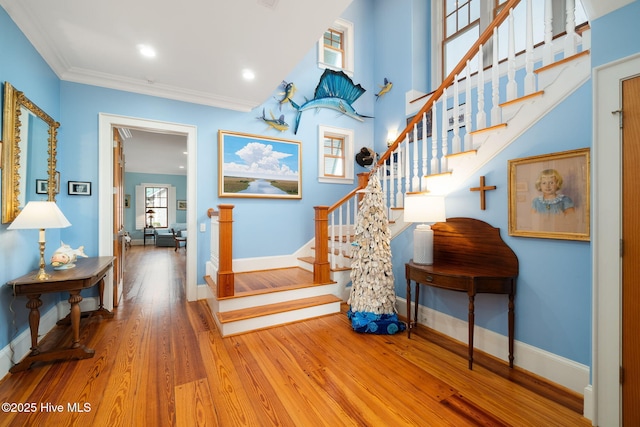 stairs with wood finished floors, baseboards, and ornamental molding