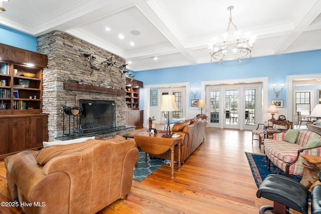 living room with coffered ceiling, light wood finished floors, beam ceiling, a fireplace, and a chandelier