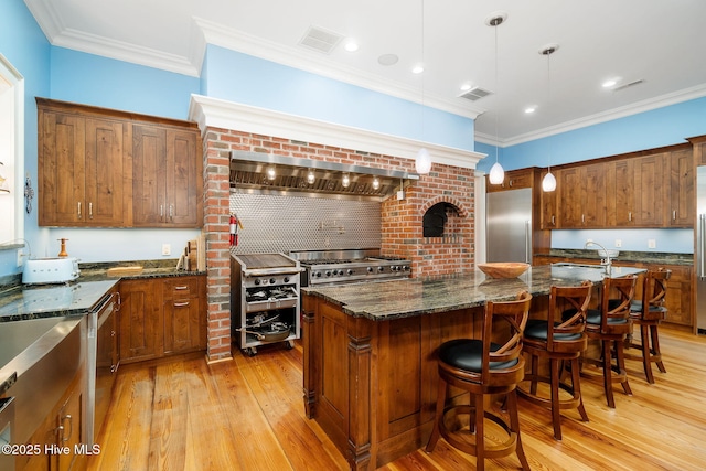 kitchen featuring visible vents, premium range hood, ornamental molding, stainless steel appliances, and a sink