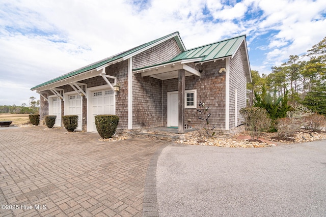 view of front of house with a standing seam roof, metal roof, decorative driveway, and a garage