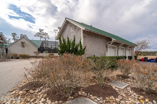 view of property exterior featuring glass enclosure and metal roof