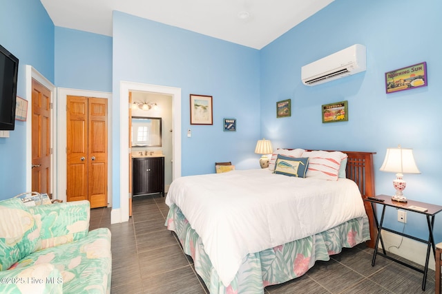 bedroom with ensuite bath, dark tile patterned floors, a closet, and a wall mounted air conditioner