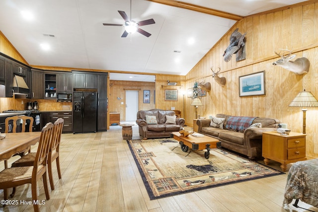 living area with wooden walls, a ceiling fan, visible vents, high vaulted ceiling, and light wood-style flooring