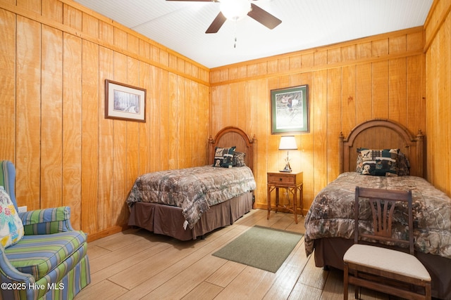 bedroom with wood finished floors, wood walls, and ceiling fan