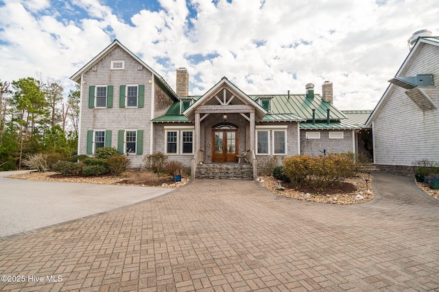 view of front of property with french doors, a chimney, decorative driveway, metal roof, and a standing seam roof