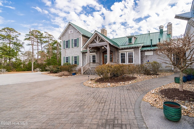 view of front of house with a chimney, decorative driveway, a standing seam roof, and metal roof