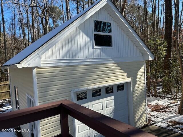 snow covered property featuring a garage and an outdoor structure