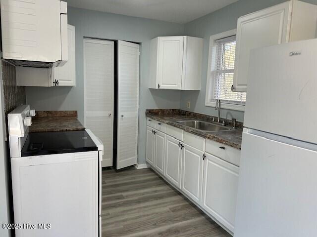 kitchen with sink, range, white cabinets, dark hardwood / wood-style flooring, and white fridge