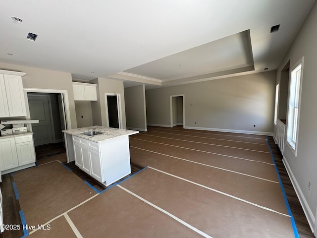 kitchen featuring a center island, white cabinets, baseboards, and a tray ceiling