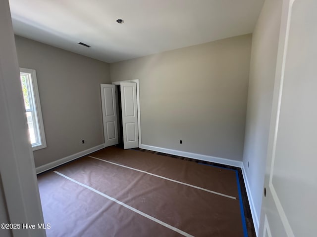 unfurnished bedroom featuring baseboards, visible vents, and dark colored carpet